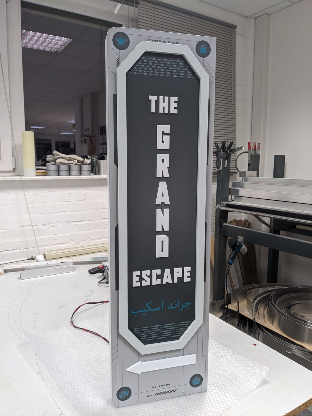 ESCAPE — Schriftzug mit eingelasertem Binärcode und arabischer Typo