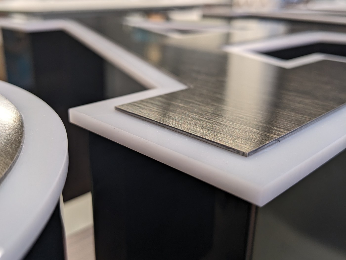 Detail einer Zarge mit weißer Acrylkante und gebürsteter Metallfront